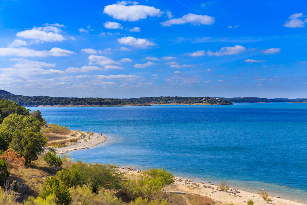 View of shore line from Canyon Lake  cabins with hills in the background and blue water 