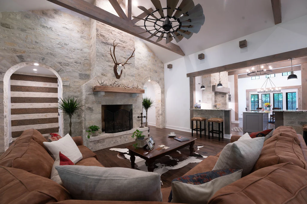 A large white and wood living room with brown couches and a large fire place in the Main Lodge of the Lost Creek Lodge, one of the best rentals with a hot tub in Fredericksburg.