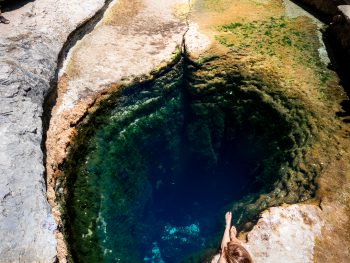 A woman overlooks Jacob's Well with its perfect blue waters and natural limestone around it.