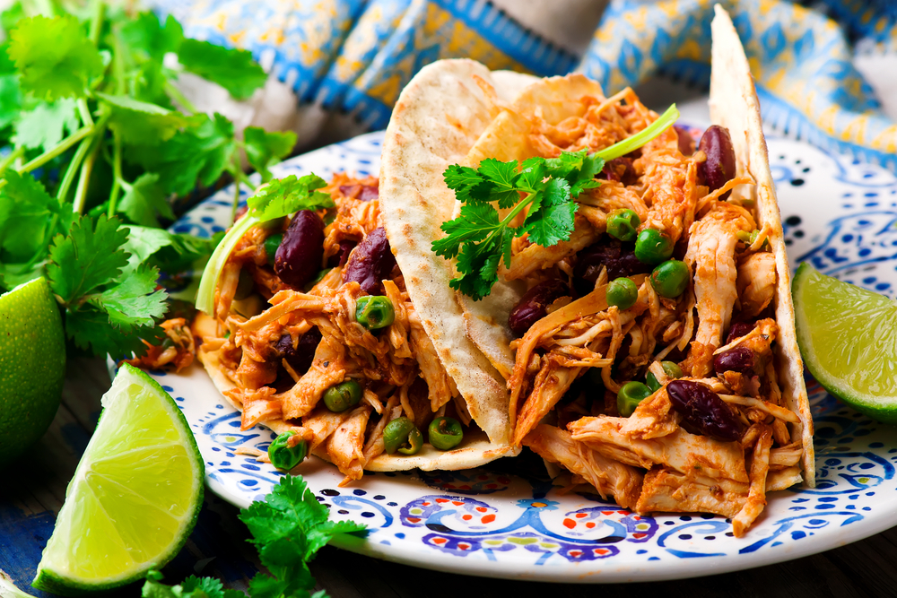 shredded chicken tacos on a colorful plate with limes