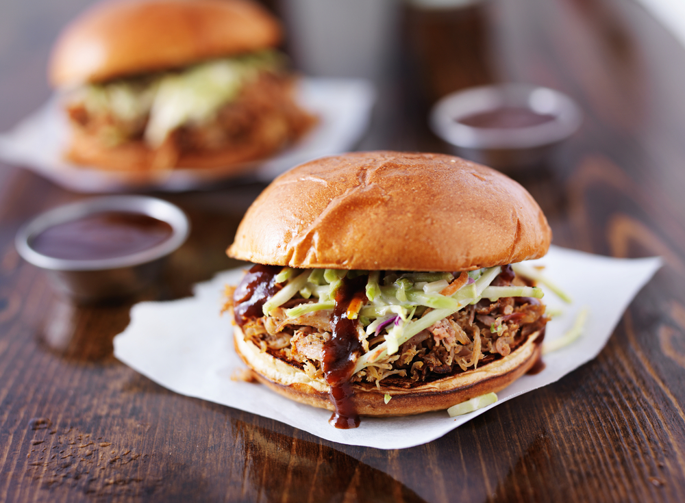 a pulled pork sandwich with slaw and barbecue sauce