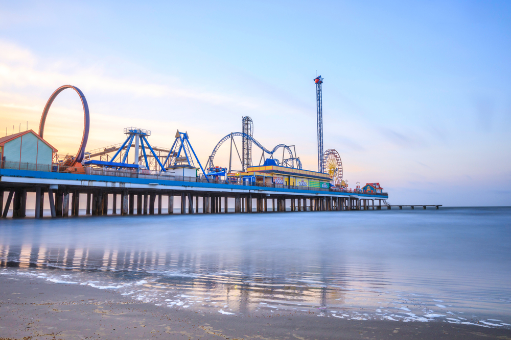 a photo of the pier in Galveston with rollercoaster and rides at dusk
