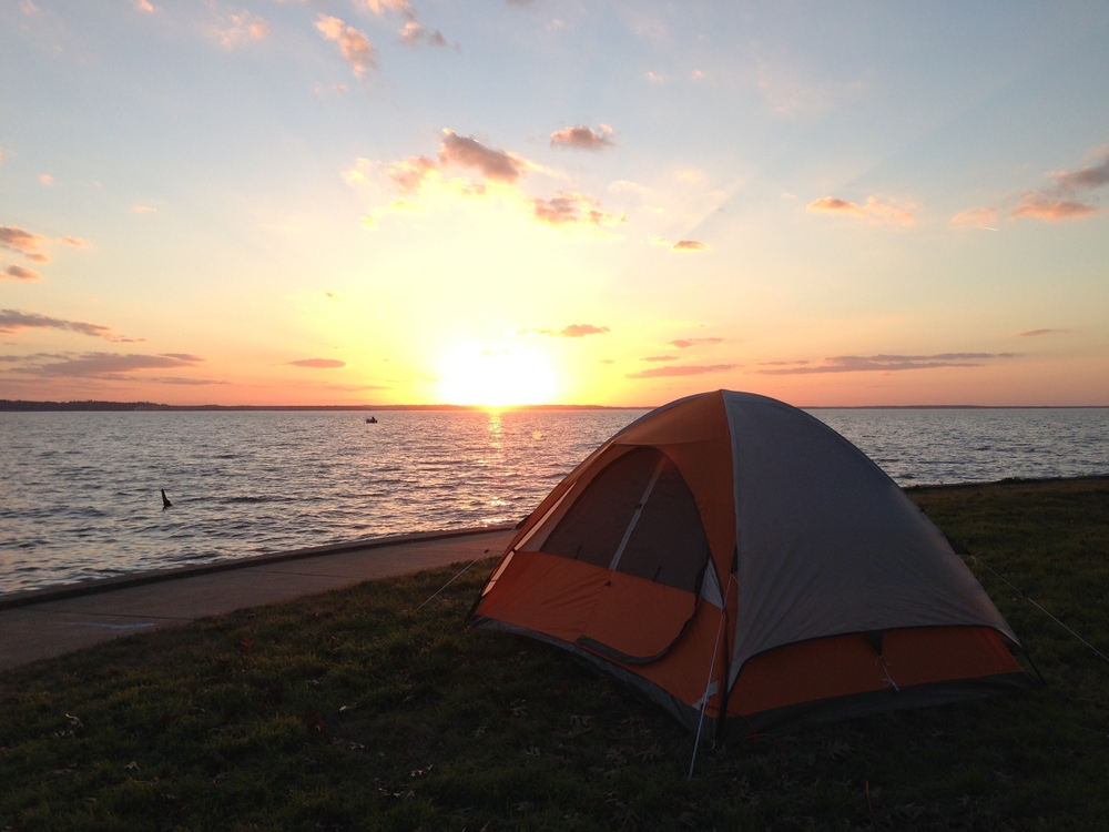 camp set up beside lake while sun sets