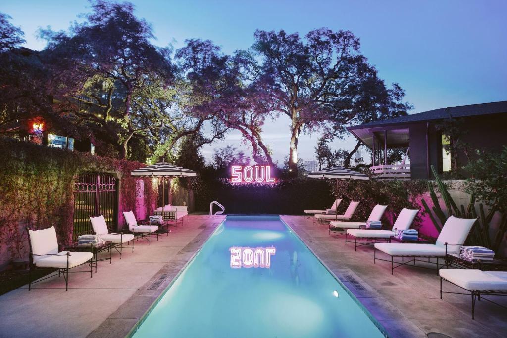 An outside swimming pool surrounded with white chairs and a neon sign in the background at one of the resort hotels in Texas