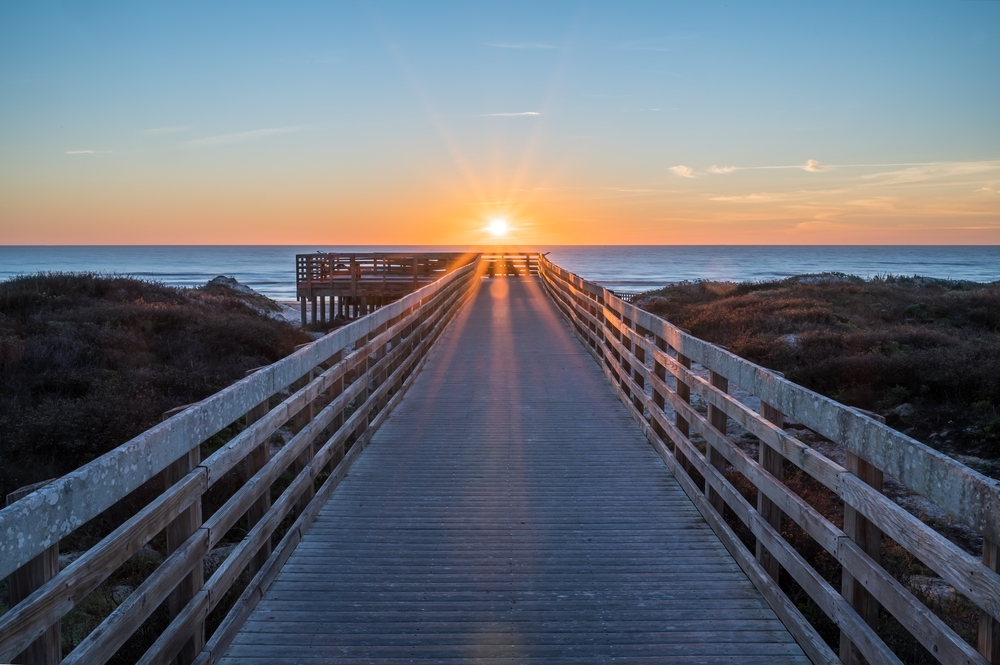 sunrise on a boardwalk surrounded by lands and water