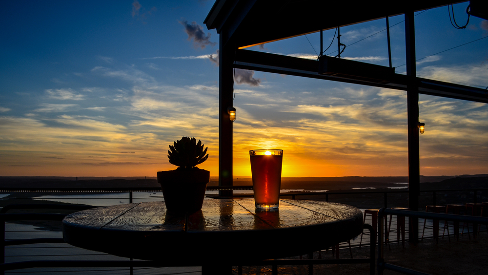 glass of beer on a table during sunset