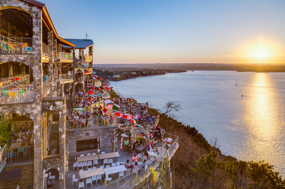 sunset above lake with a restaurant on the side things to do in lake travis