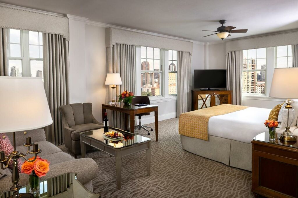 spacious room with a bed, sofa set, TV, and multiple windows best boutique hotels in dallas