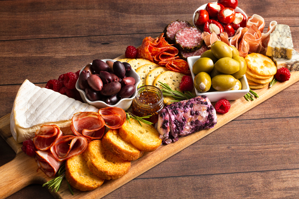 A charcuterie board loaded with cheeses, olives, meats, crackers, and  crostini. Restaurants in San Antonio like Bliss offer such delights