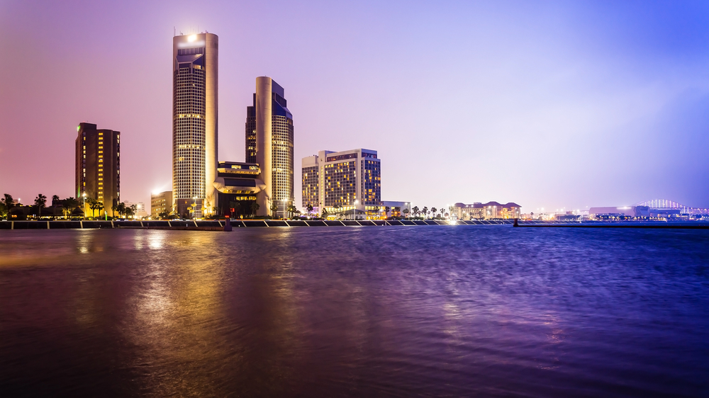 One of the best weekend getaways from Dallas is the city of Corpus Christi as shown at dusk as the city skyline runs right up to twilight colors of the ocean. 
