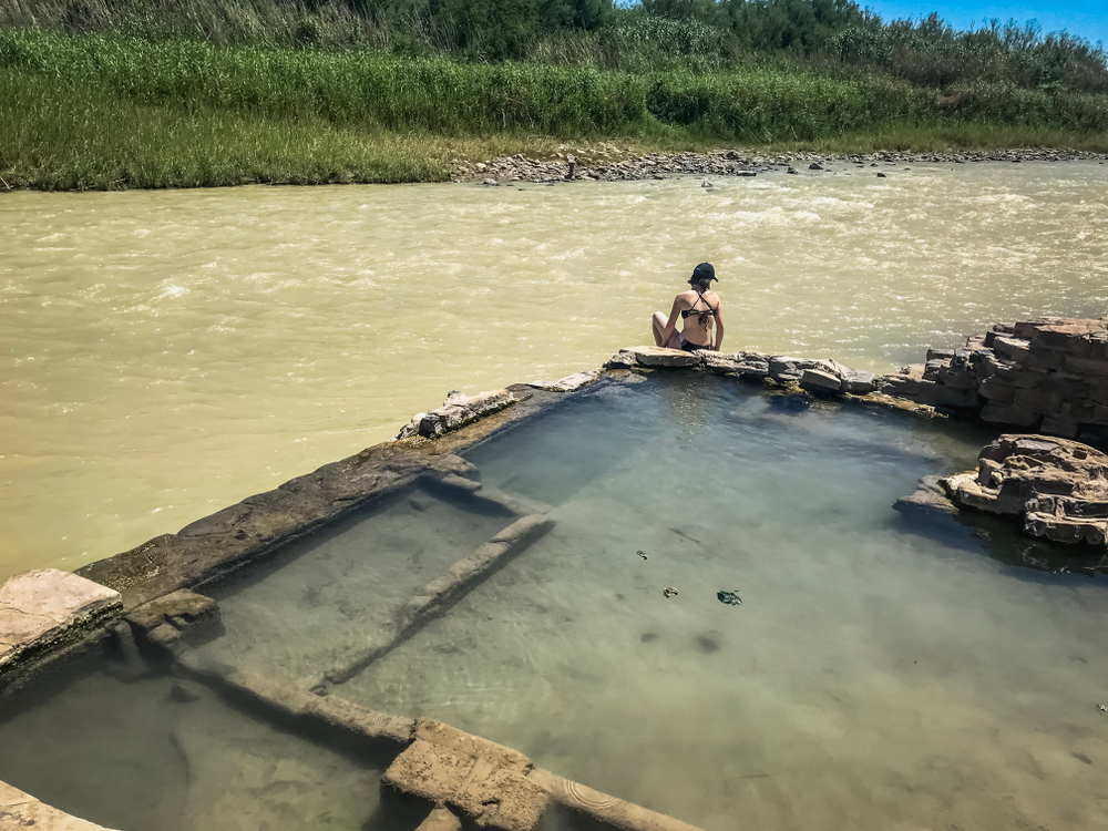 Woman sitting on the edge of Big Bend National Park Hot Springs overlooking the river.