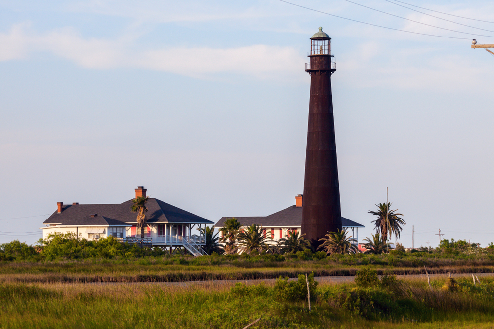 A lighthouse among some houses and palm trees
