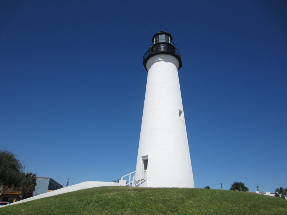 A white lighthouse on top of a green bank