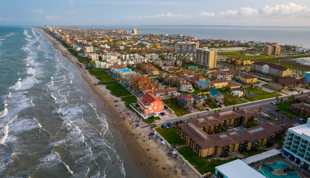 An aerial view of a beach town in Texas with houses a beach and the sea with small waves