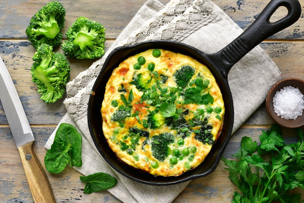 An omelet cooked in a skillet with broccoli and spinach with a drizzle of sea salt is served in a restaurant in Fredericksburg. 