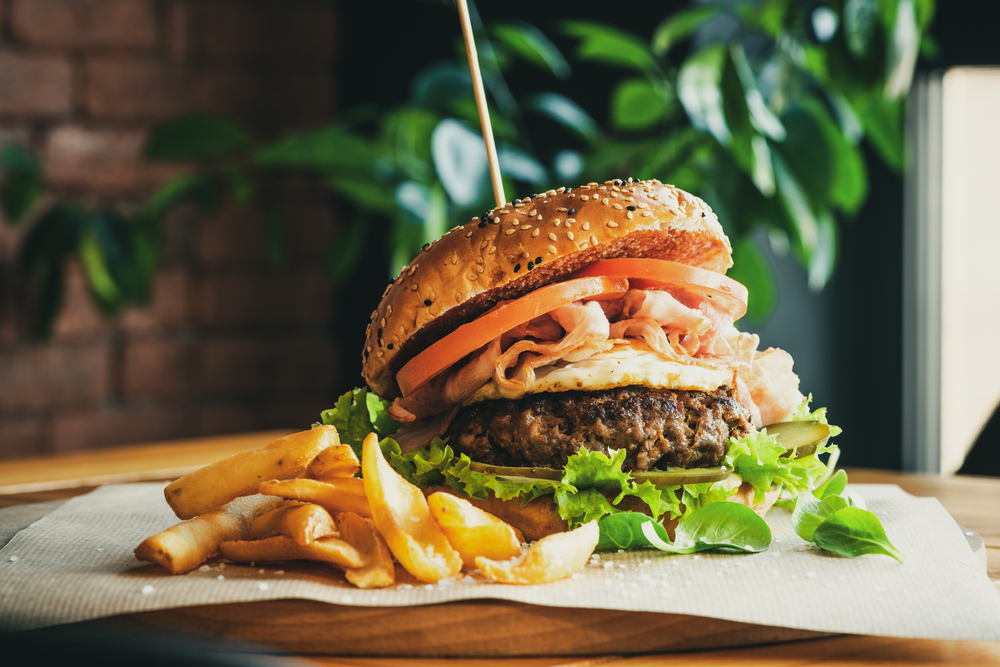 A restaurant in Fredericksburg servers a burger with tomatoes lettuce and a fried egg with a side of sea salt fries. 