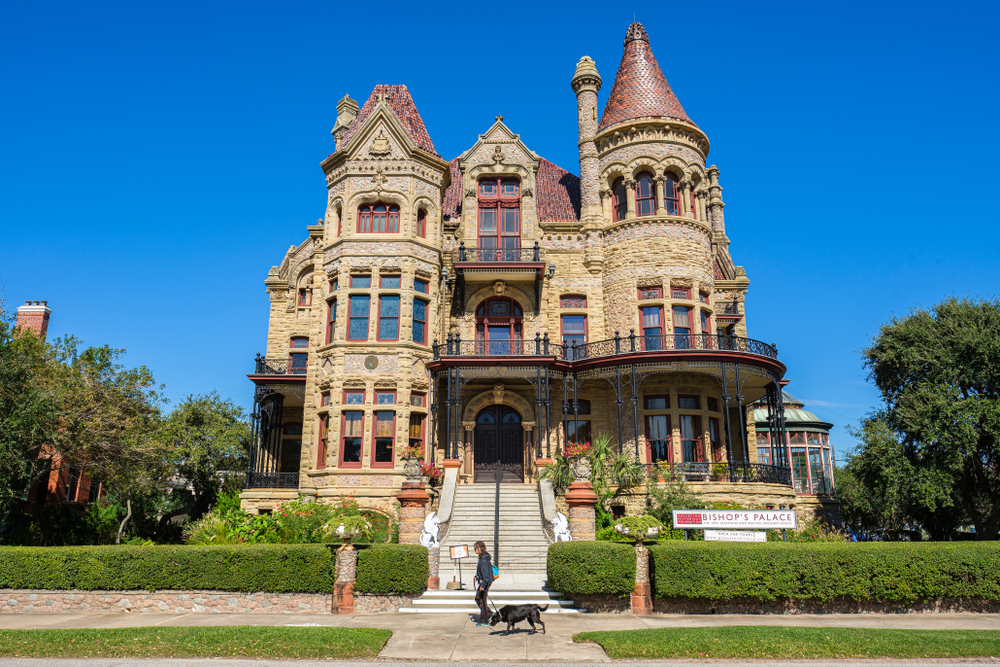 Woman walking dog in front of Bishop's Palace in Galveston, TX. A castle in Texas