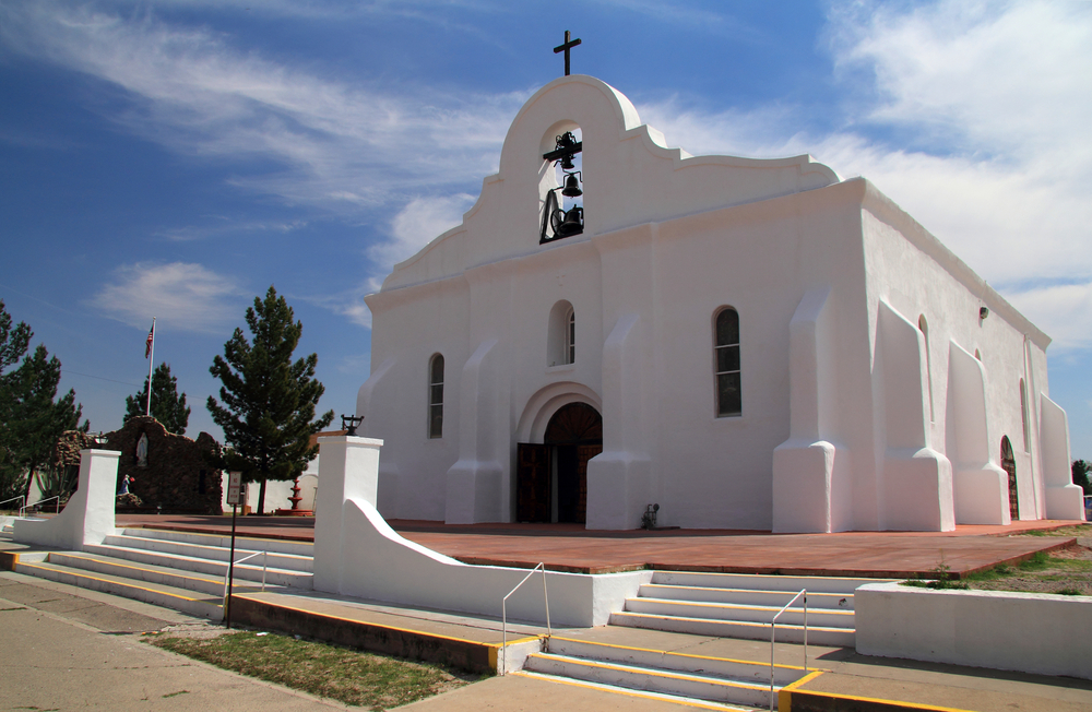 White mission building with steps and bells in one of the most historic cities in Texas