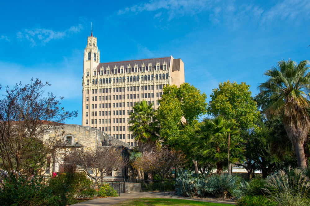 A tall old styled building named The emily morgan hotel with trees in the foreground on a sunny day one of the most haunted places in texas