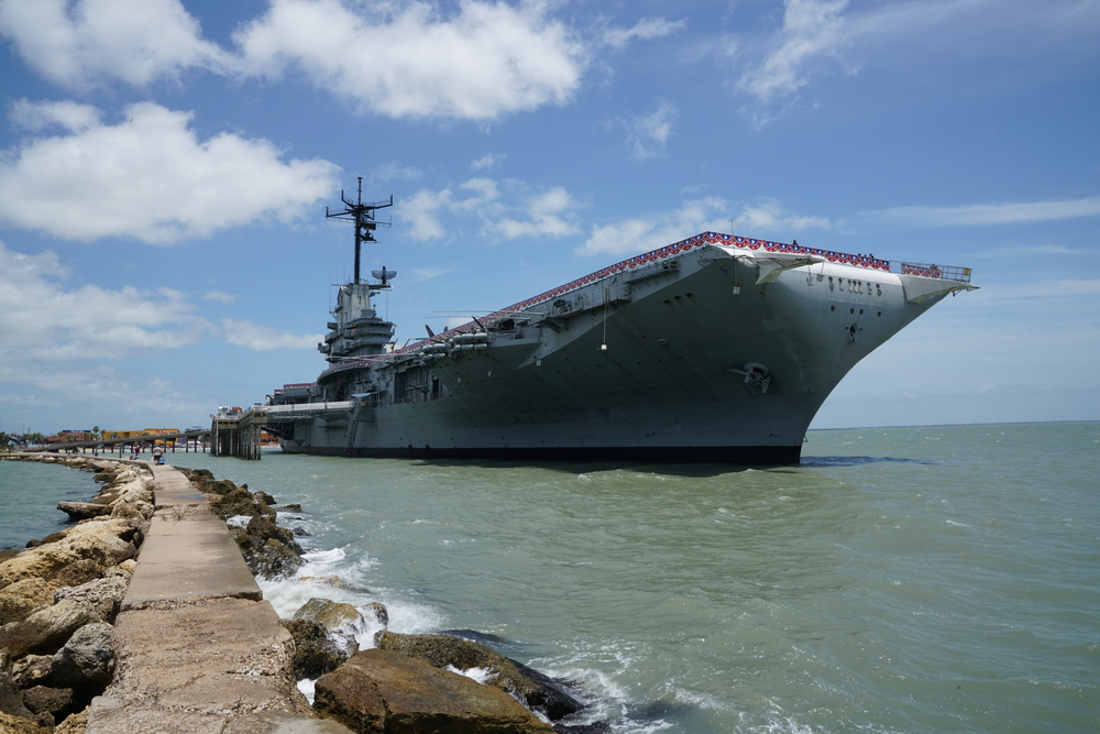 A large ship named The USS Lexington docked on a sunny day