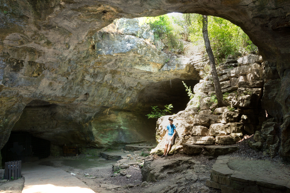 Teenager Is Sitting On A Rock Entrance To The Longhorn. One of the hidden gems in Texas