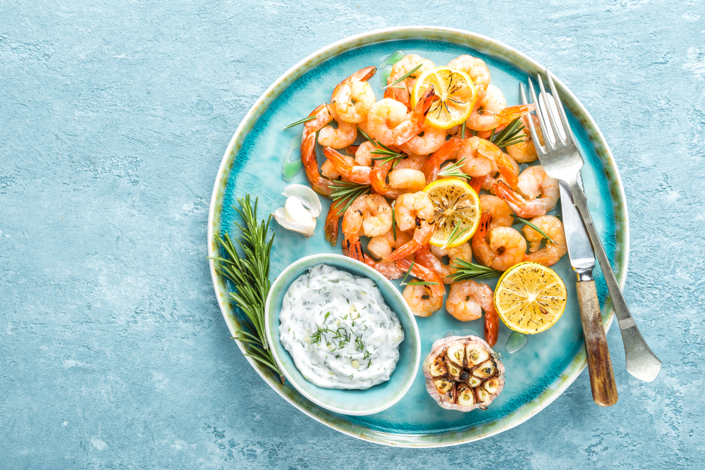 Pan seared shrimp is served with a side of aioli, lemon wheels, and seared garlic at a restaurant in Fredericksburg.