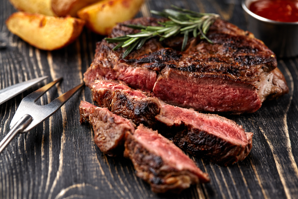 A chargrilled medium rare stake is sliced and served with potatoes and topped with a sprig of rosemary at a restaurant in Fredericksburg.