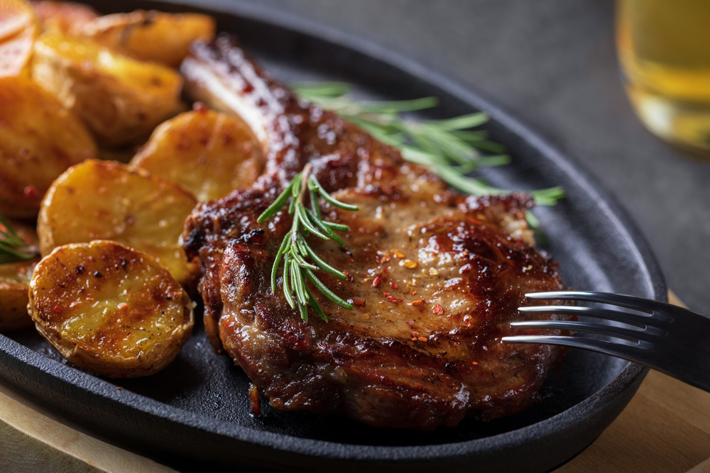 A black plate with a large steak, grilled potatoes, and sprigs of rosemary. Its similar to a meal at one of the best restaurants in Amarillo.