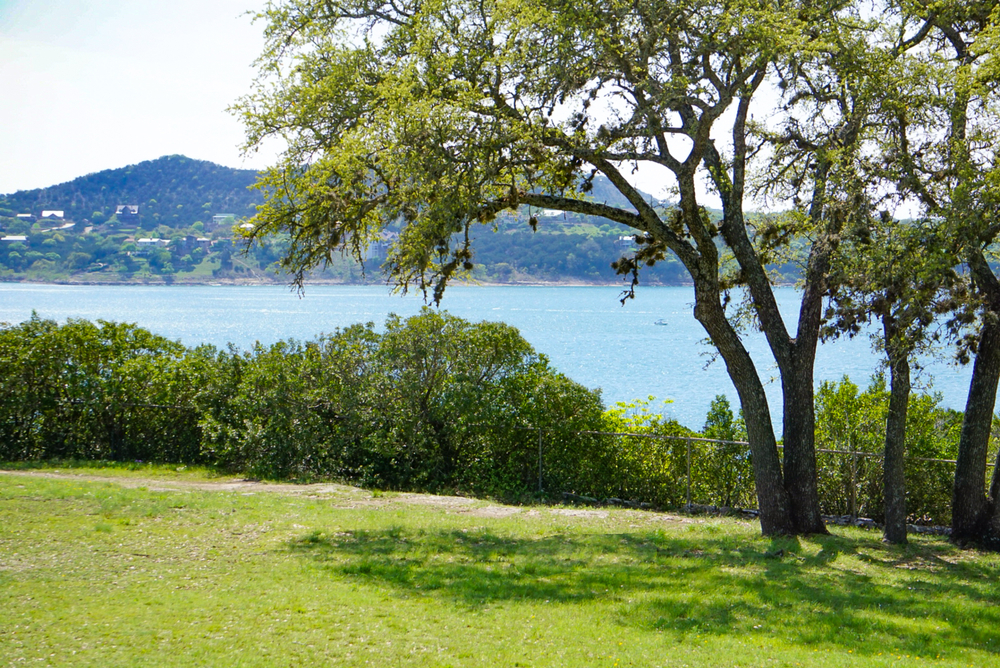 an overlook of canyon lake in Texas with trees and green grass at high noon