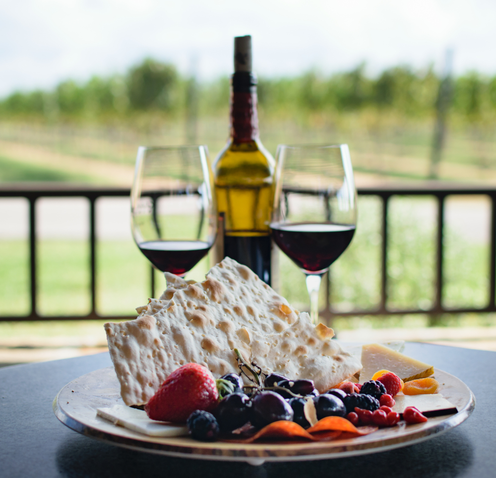 Plate with fruit, cheese, and crackers with wine.