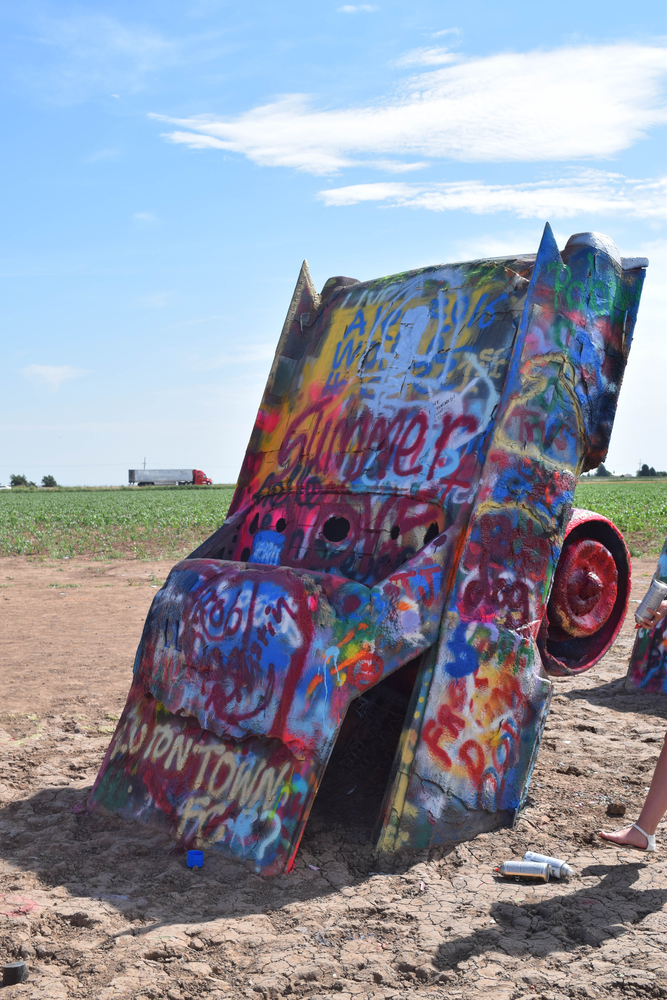 photo of a Cadillac sticking out of the ground covered in spray painting 