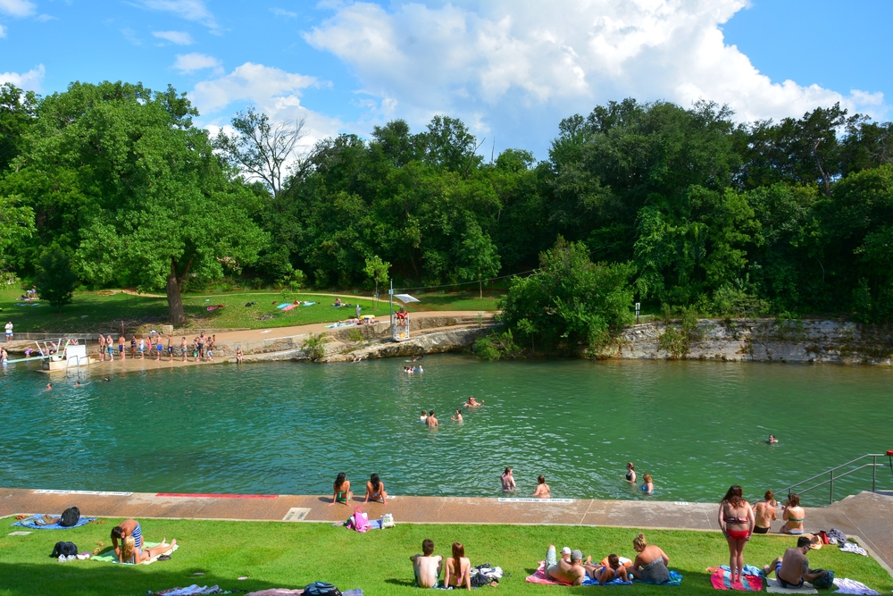 People relaxing on a nice sunny day at the crystal blue waters of Barton Springs Pool