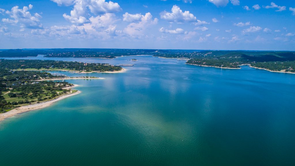 A wide aerial view of the blue waters of Lake Travis waterloo on a sunny day