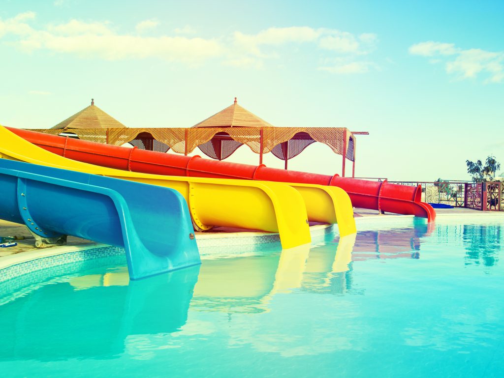 Multi-colored slides at amusement parks in Texas, that lead to a bright blue pool.