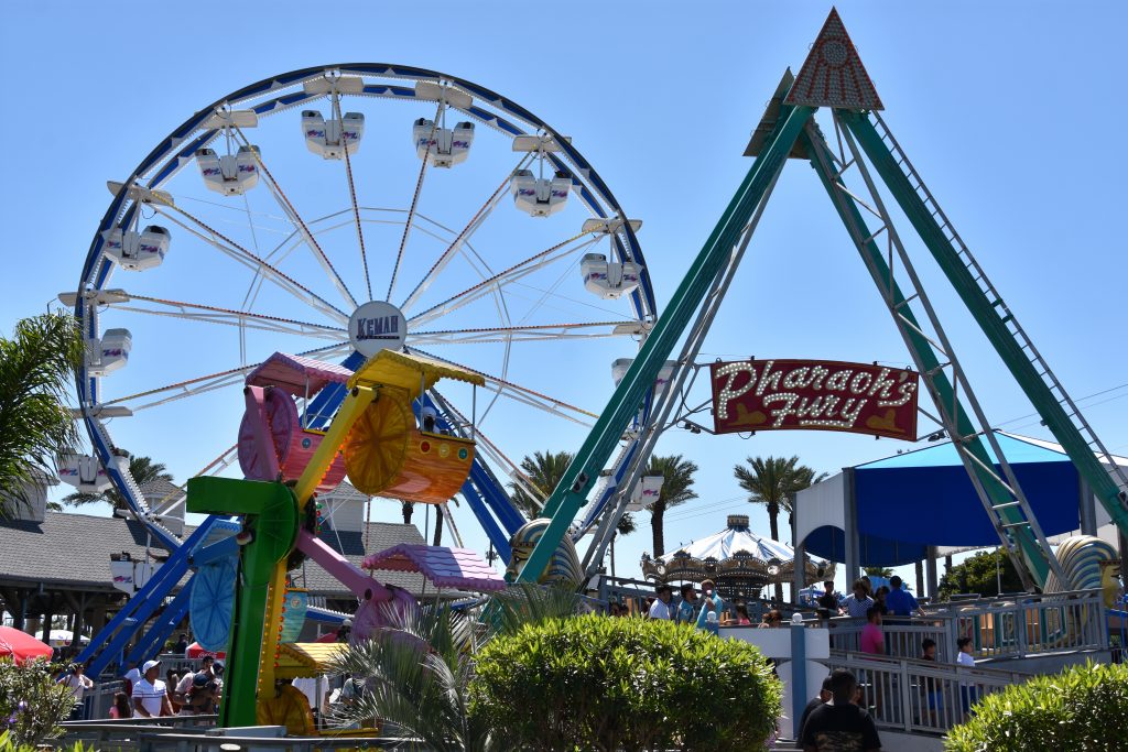 Farris Wheel at amusement parks in Texas surrounded by families on a sunny, blue day.