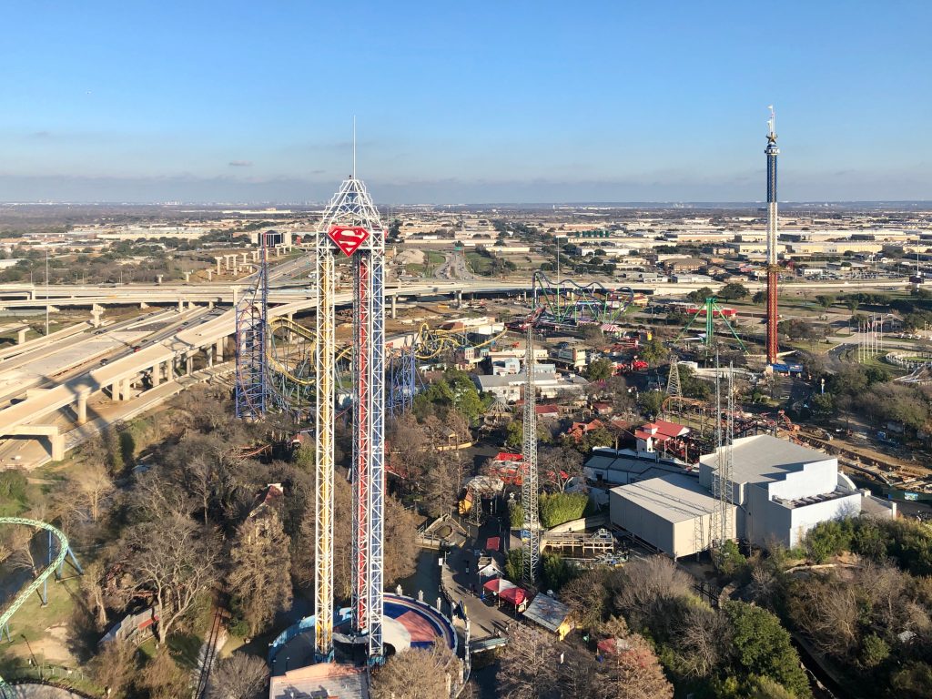 Amusement parks in Texas tower over the city of Arlington with views of the city and blue skies. 