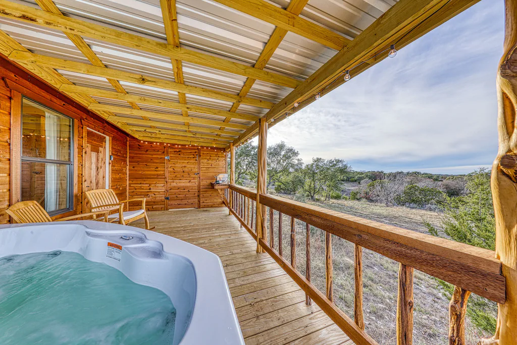 Overlook of a wooden porch with a hot tub and rocking chairs.