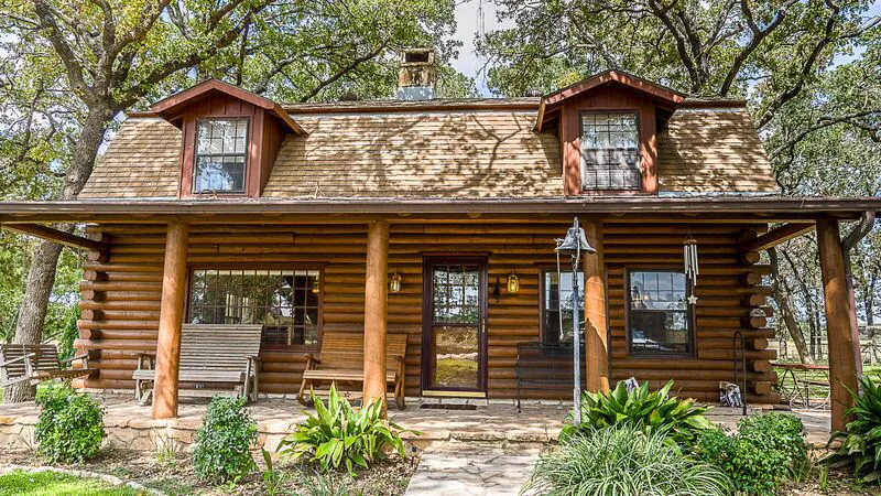 A large wooden cabin with dormers, the Comanche Homestead, one of the best rentals in Fredericksburg, Texas.