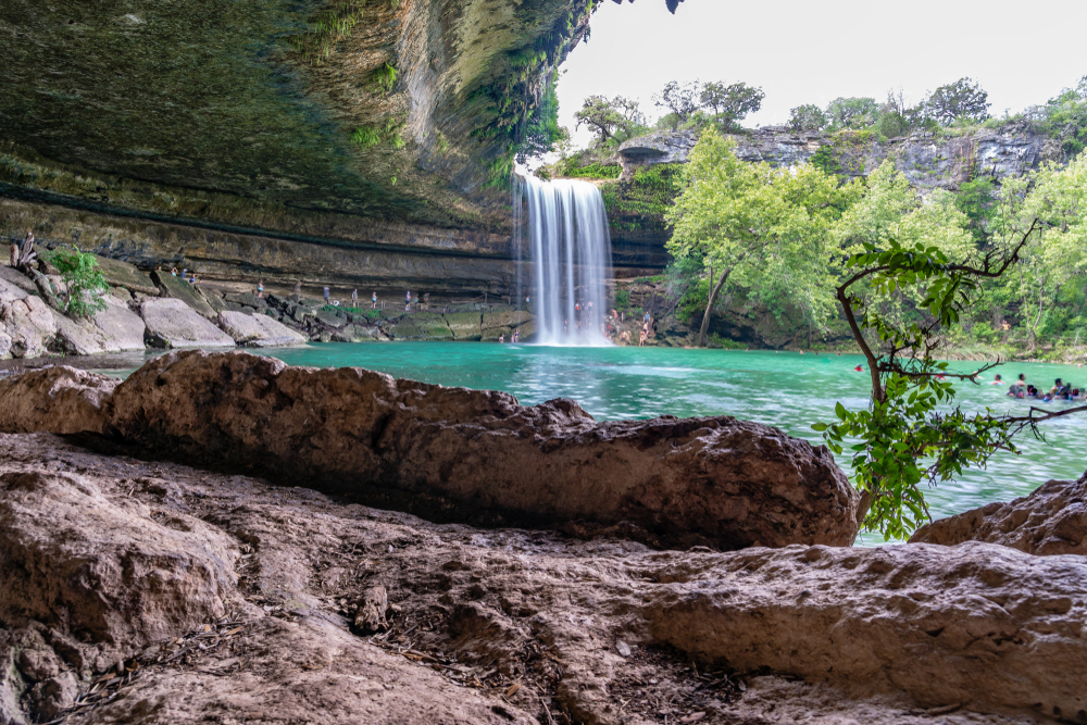 waterfall cascading into turquoise lake surrounded by pink rocks day trips from Austin
