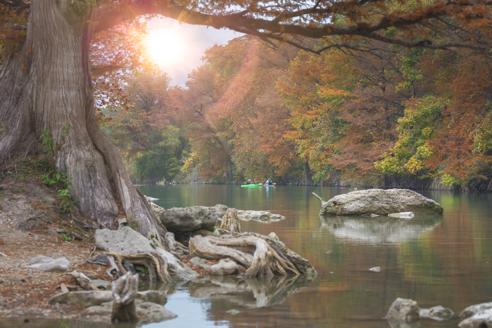A serene spot on the Guadalupe River for kayaking in Texas where two kayakers are enjoying an afternoon in this photo.