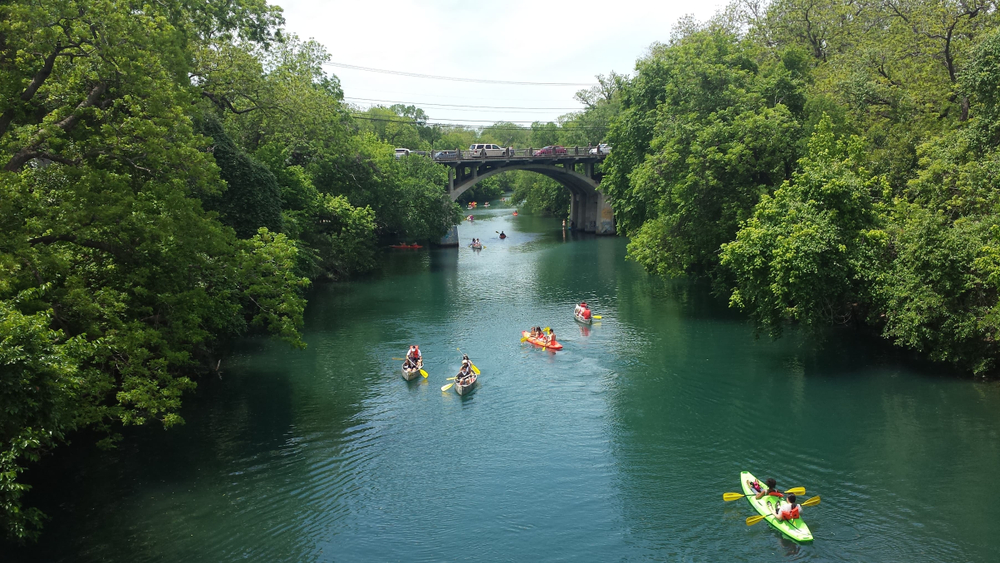  Le kayak sur le lac Lady Bird est l'un des endroits les plus uniques pour faire du kayak au Texas. De nombreux pagayeurs voyagent sous un pont sur cette image.