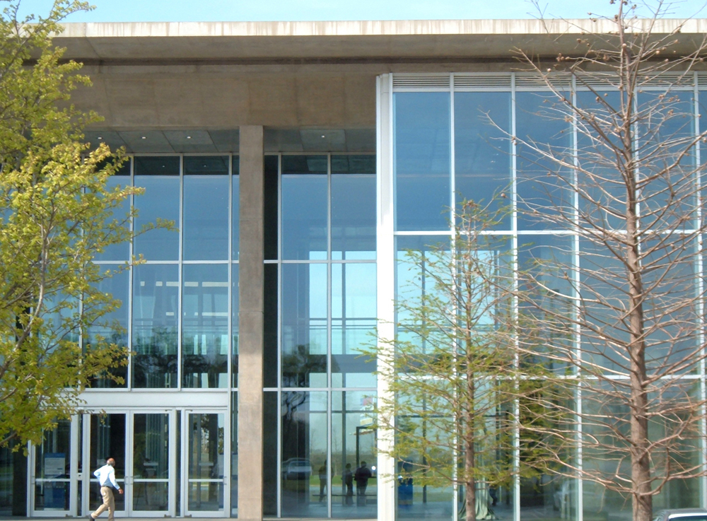 A close up of a glass building and trees in front