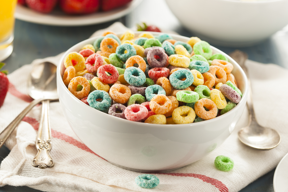 bowl of cereal with colorful round shaped cereal with spoons 