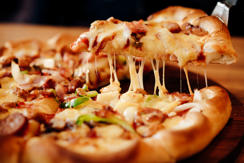 close up of slice of pizza being served with cheese strings