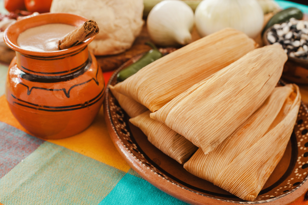 A plate of tamales next to a mug with a cinnamon stick in it at one of the best restaurants in Lubbock, Leal's Tamale Factory!