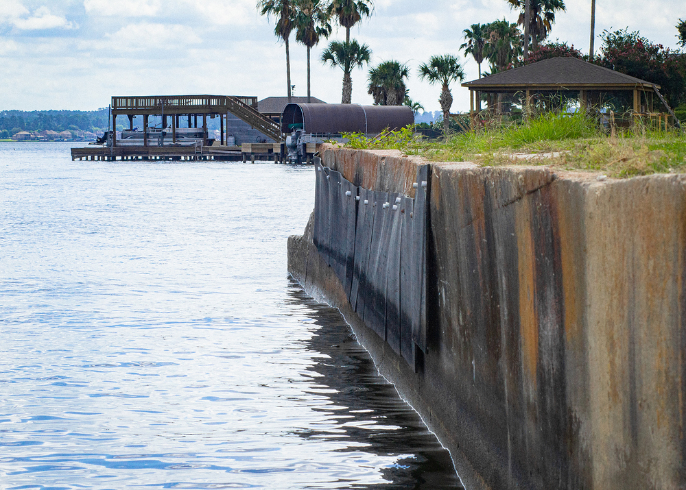 a concrete boat dock with picnic pavilions and palm trees along the water