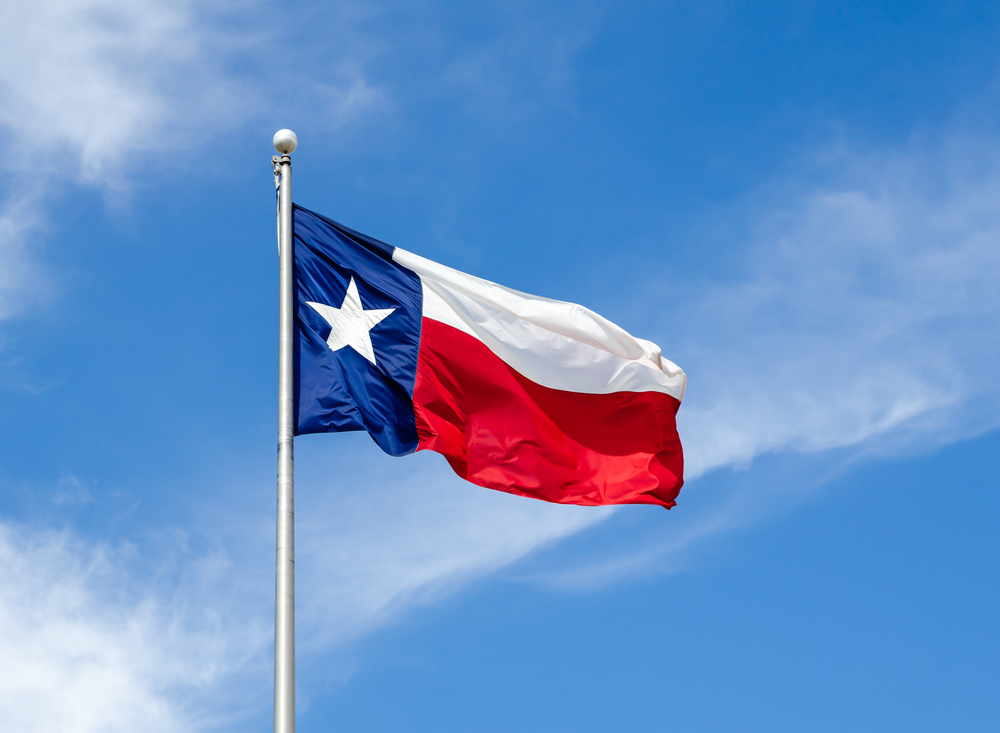 The Texas flag waves on a flag pole on a windy day one of the best things to do in conroe 