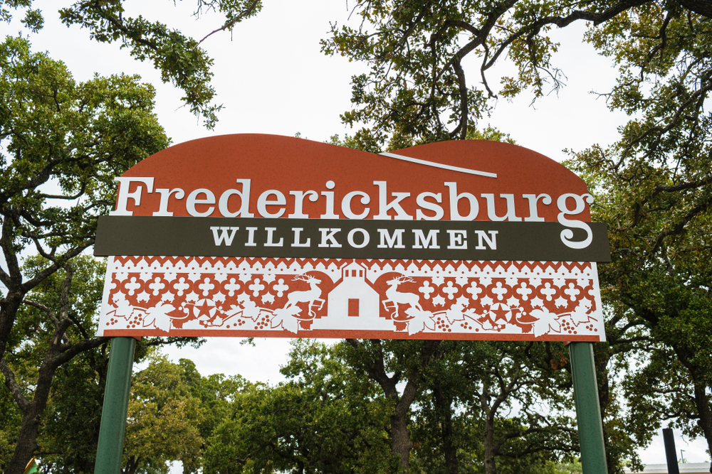 Sign in orange and brown with pattern on it says Fredericksburg Willkommen on it for wineries in Fredericksburg 