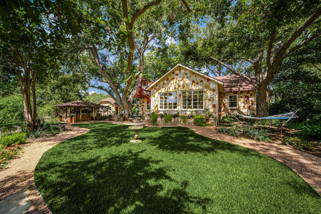 The white stone exterior of the Riverstone Cottage VRBO. The outdoor kitchen and bar is visible, as well as a comfy hammock. This is one of the best vacation rentals in Texas. 