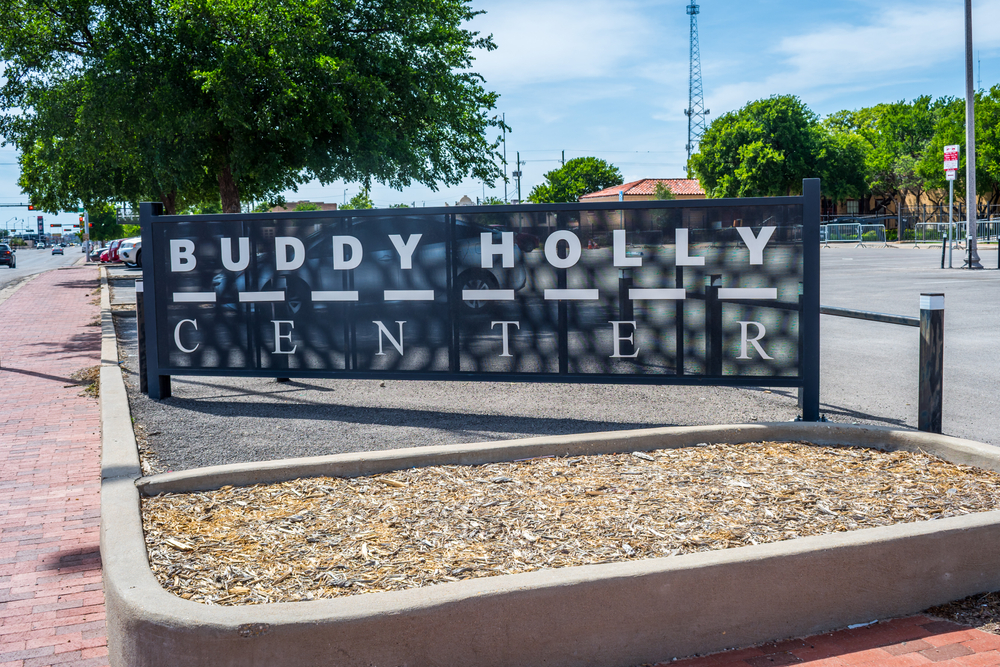 The sign in the parking lot for the Buddy Holly Center, one of the best things to do in Lubbock. It is black, kind of see through, and the words are in white. 